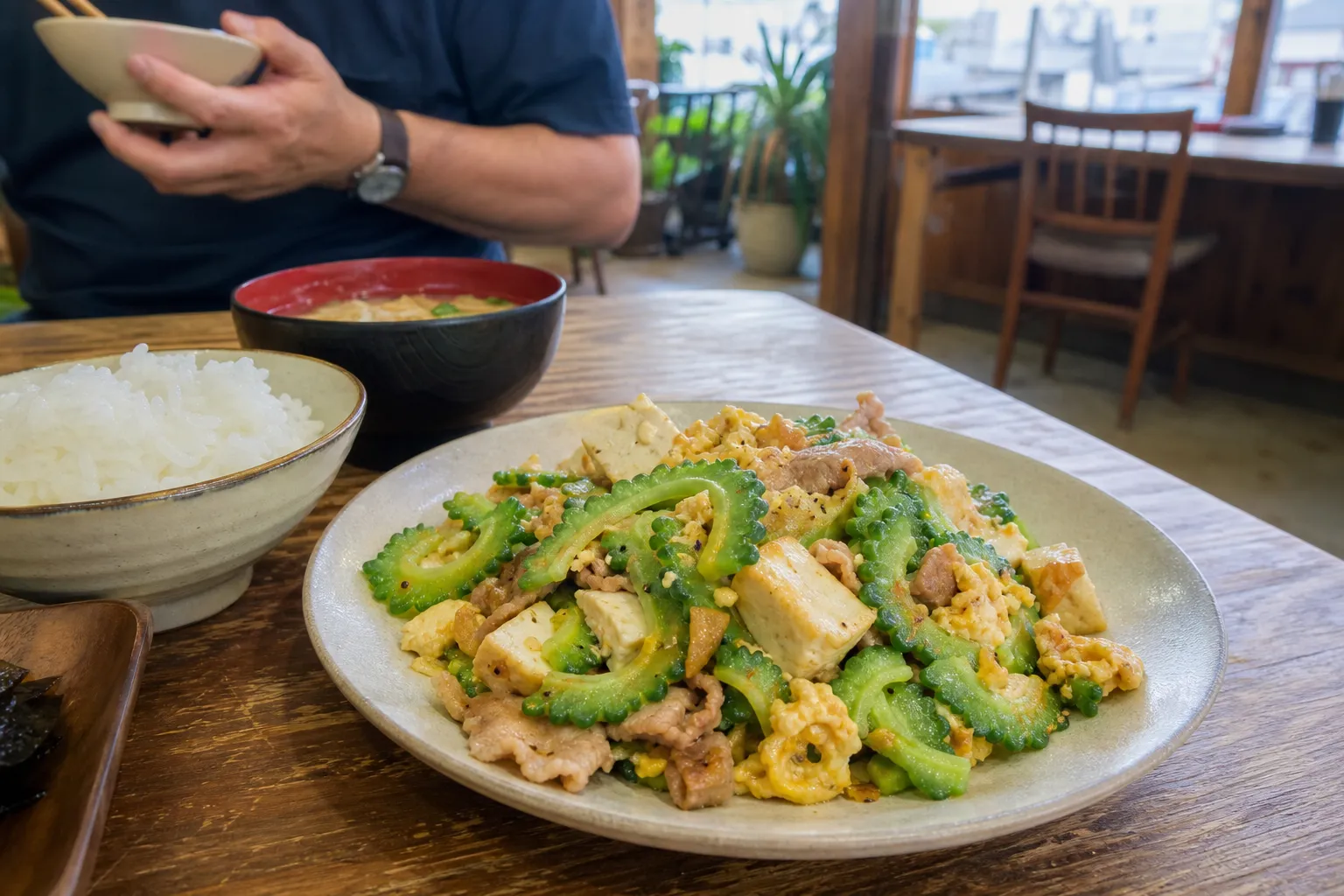 A plate of goya chanpuru with rice and miso soup at a casual Okinawan diner