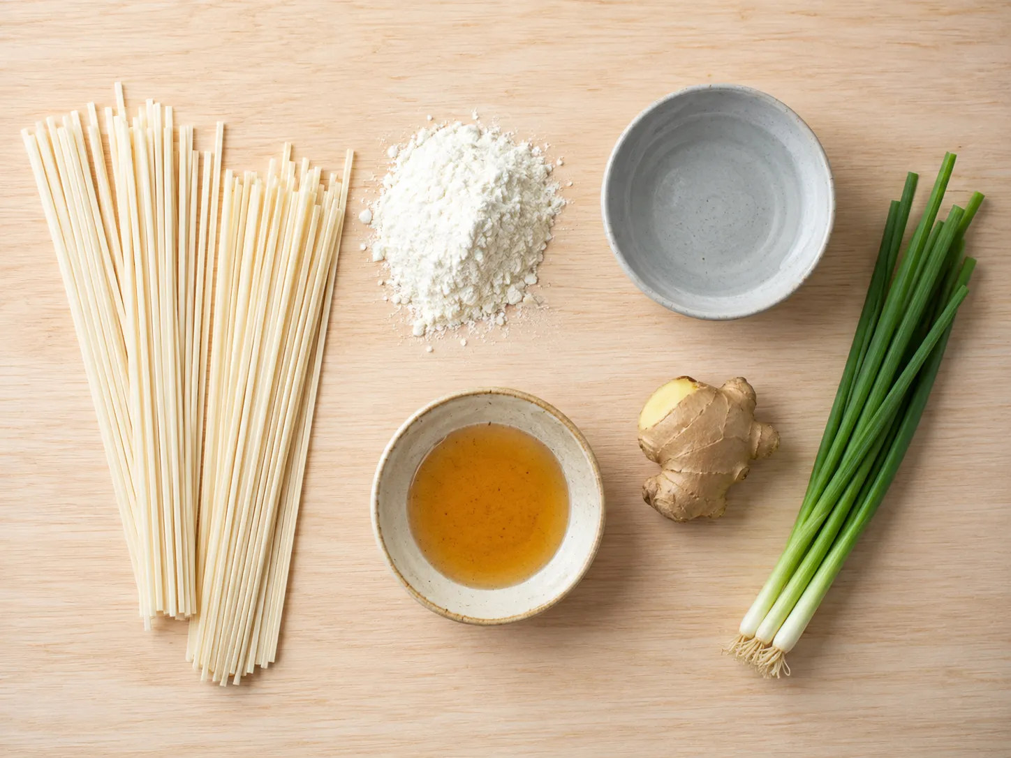 Flat lay of handa somen ingredients: bundles of dry thick somen, wheat flour, salted water, sesame oil, ginger and green onion