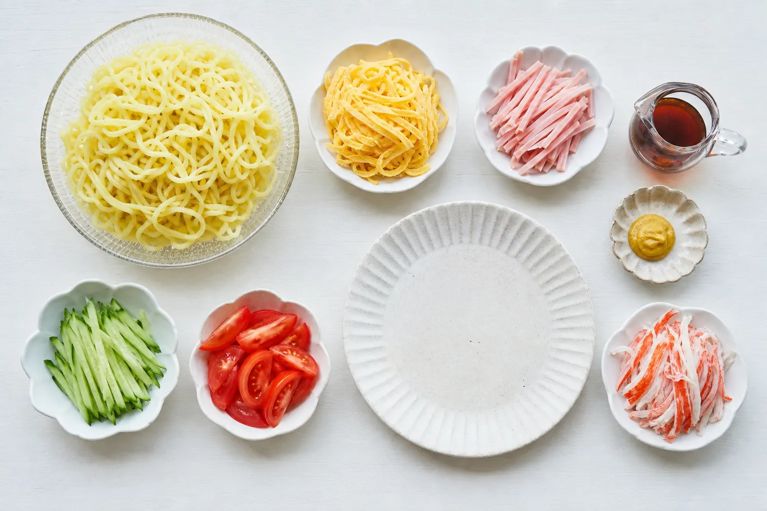 Cold noodles, strips of egg, ham, cucumber and tomato, and a soy-vinegar sauce laid out to make hiyashi chuka