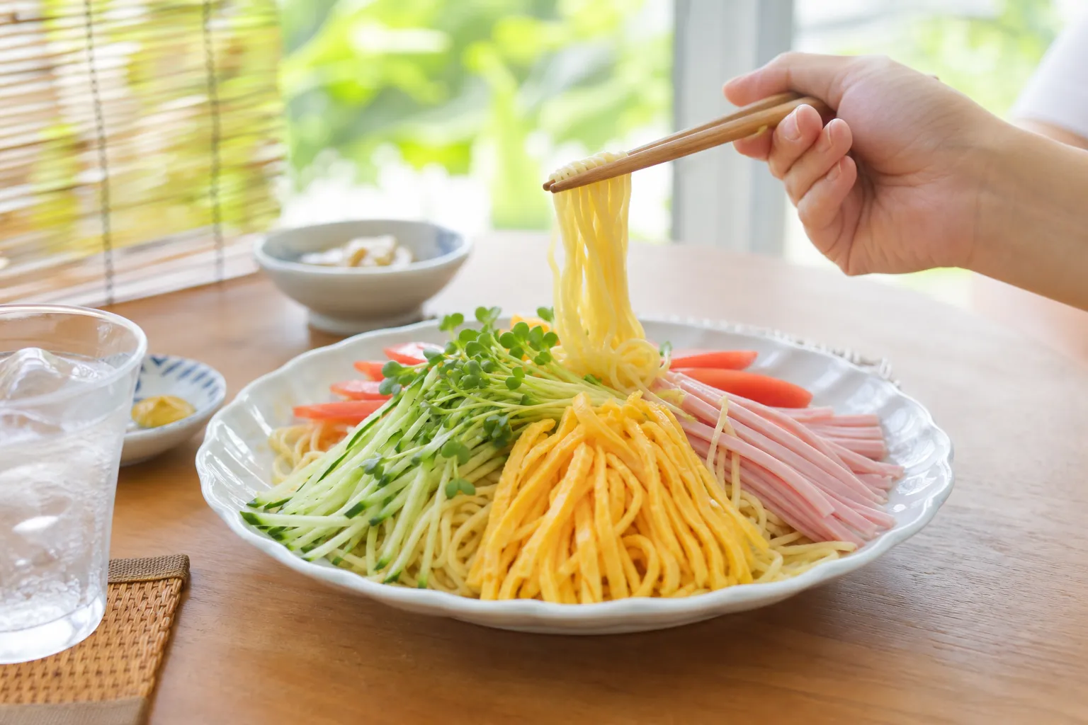 A colorful plate of hiyashi chuka on a diner table with a summer banner in the background