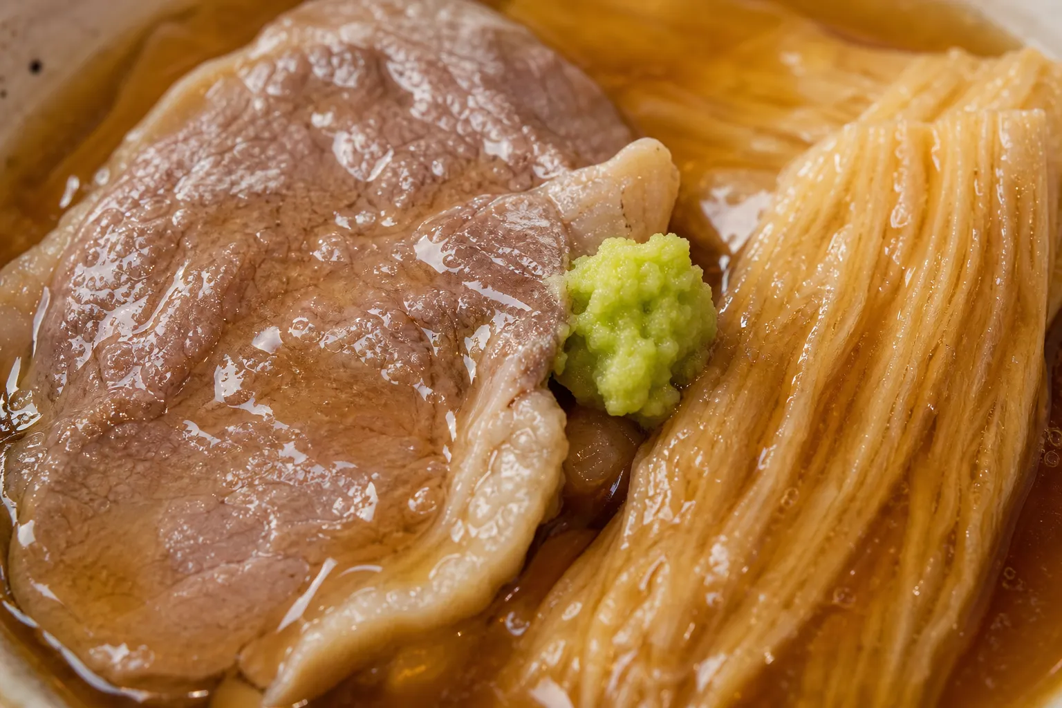 Close-up of flour-dusted duck coated in glossy thickened broth beside sudarefu
