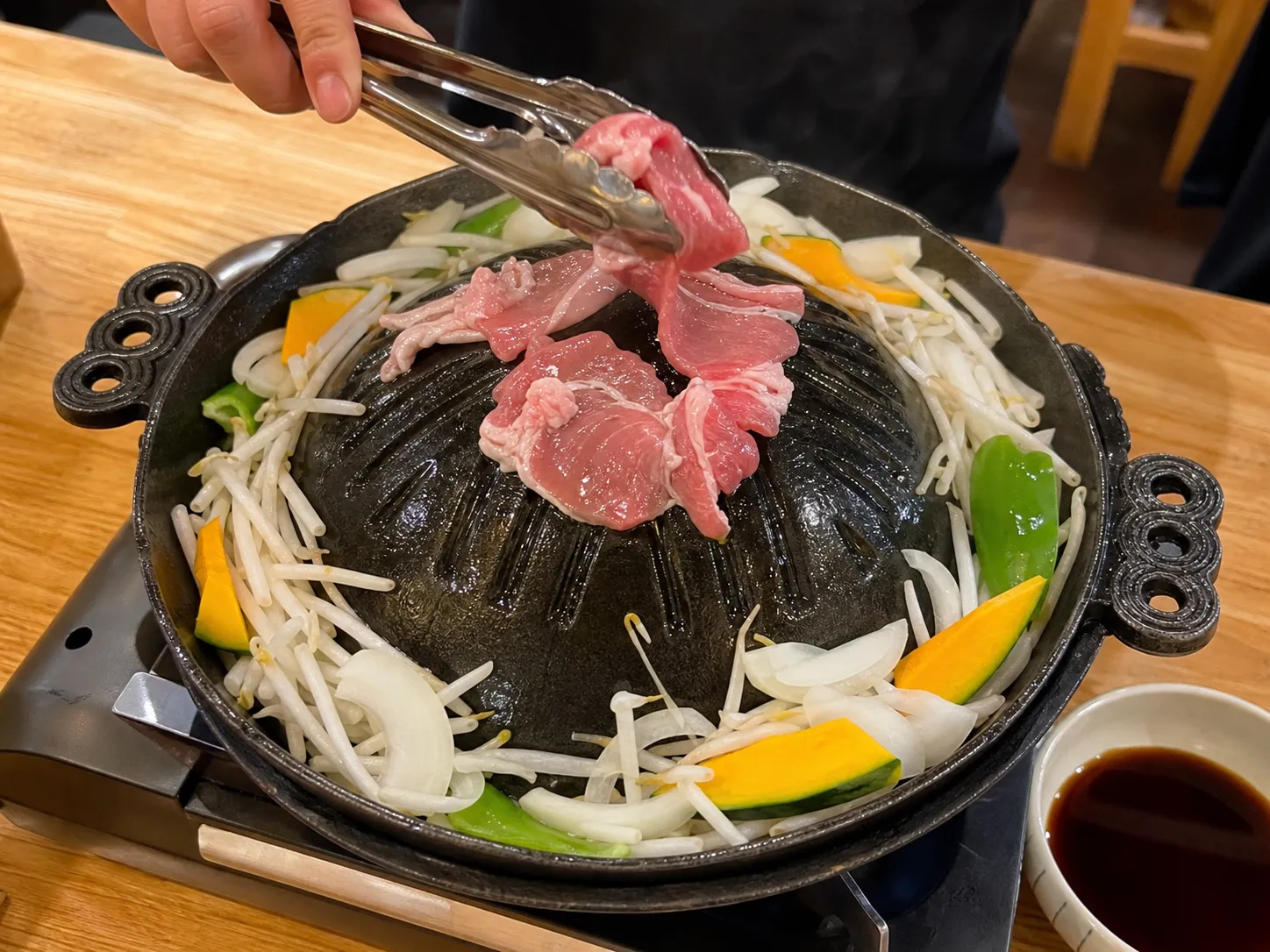 Jingisukan setup with fresh lamb and vegetables ready to grill