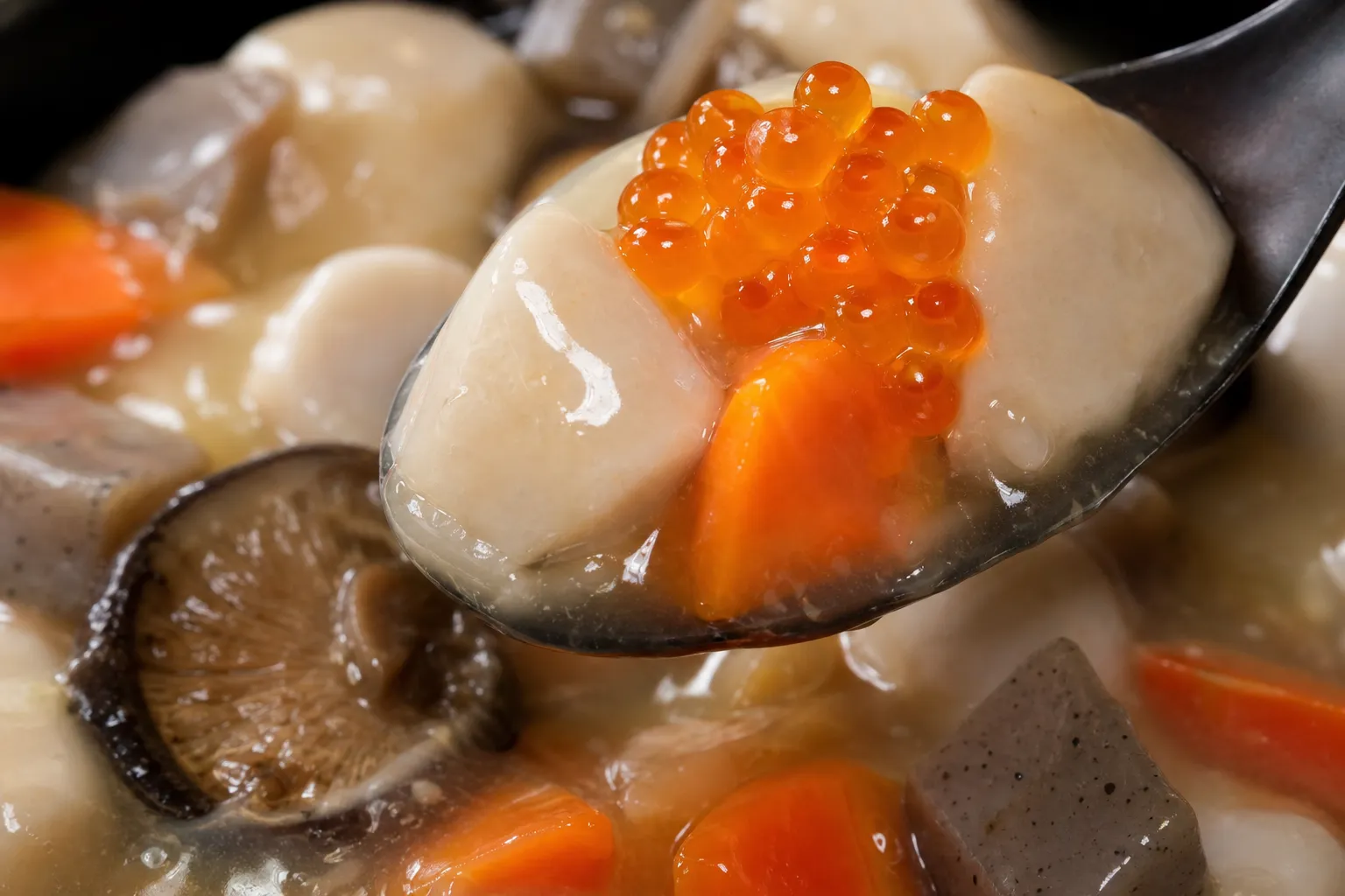Close-up of noppe stew showing glossy, lightly thickened broth with cubed taro, carrot, and konnyaku