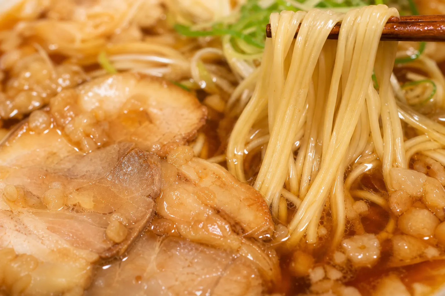 Close-up of Onomichi ramen broth dotted with pork back-fat cubes