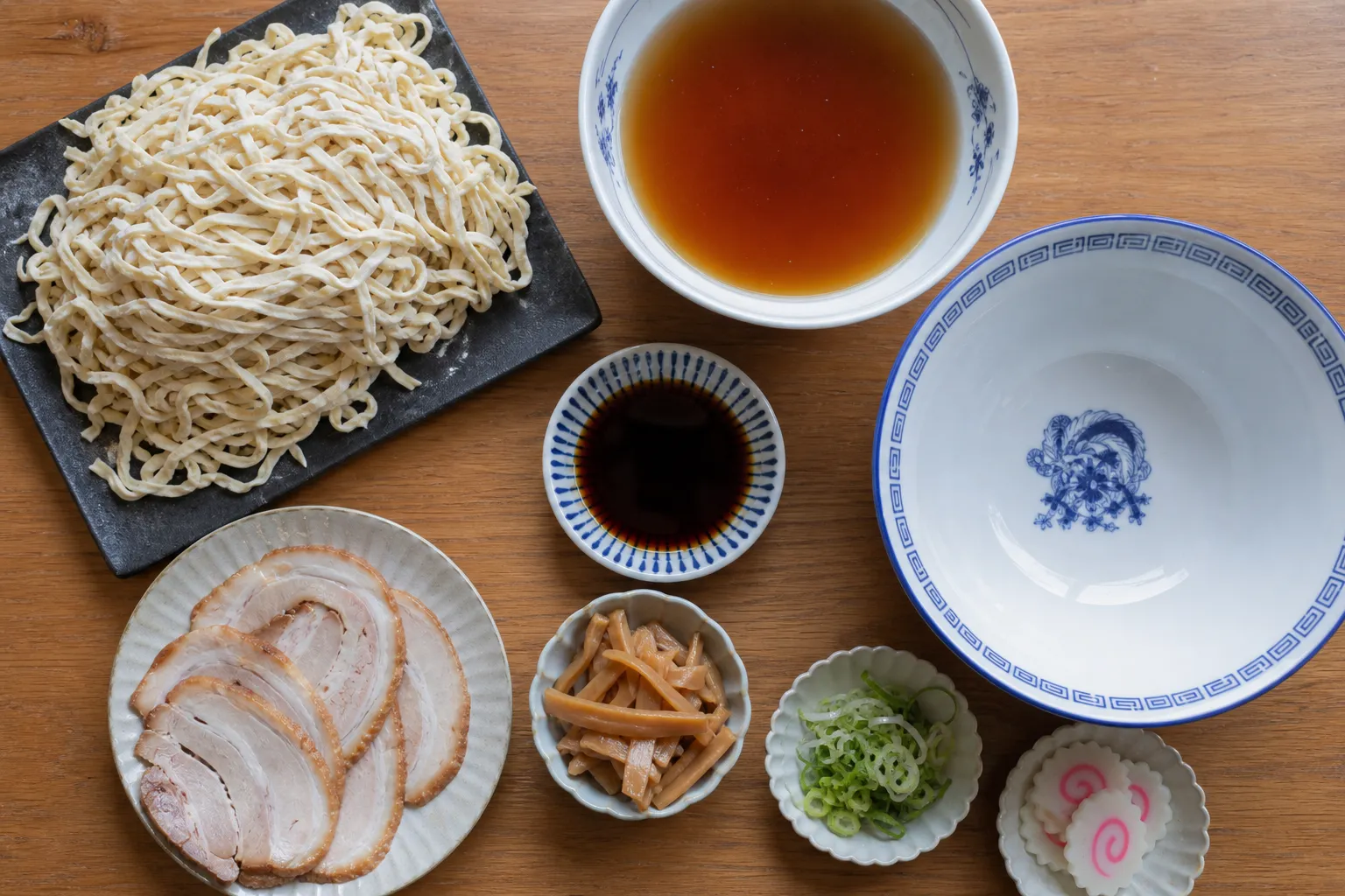 Flat hand-cut noodles, clear soy broth, chashu and menma laid out to make Sano ramen