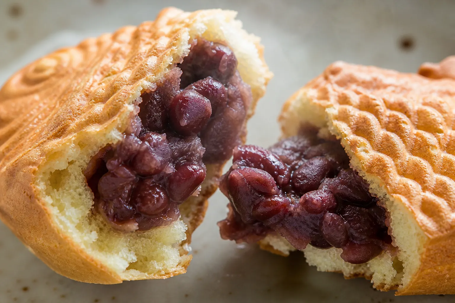 A close-up of taiyaki showing crisp fish-patterned shell and warm chunky red bean filling