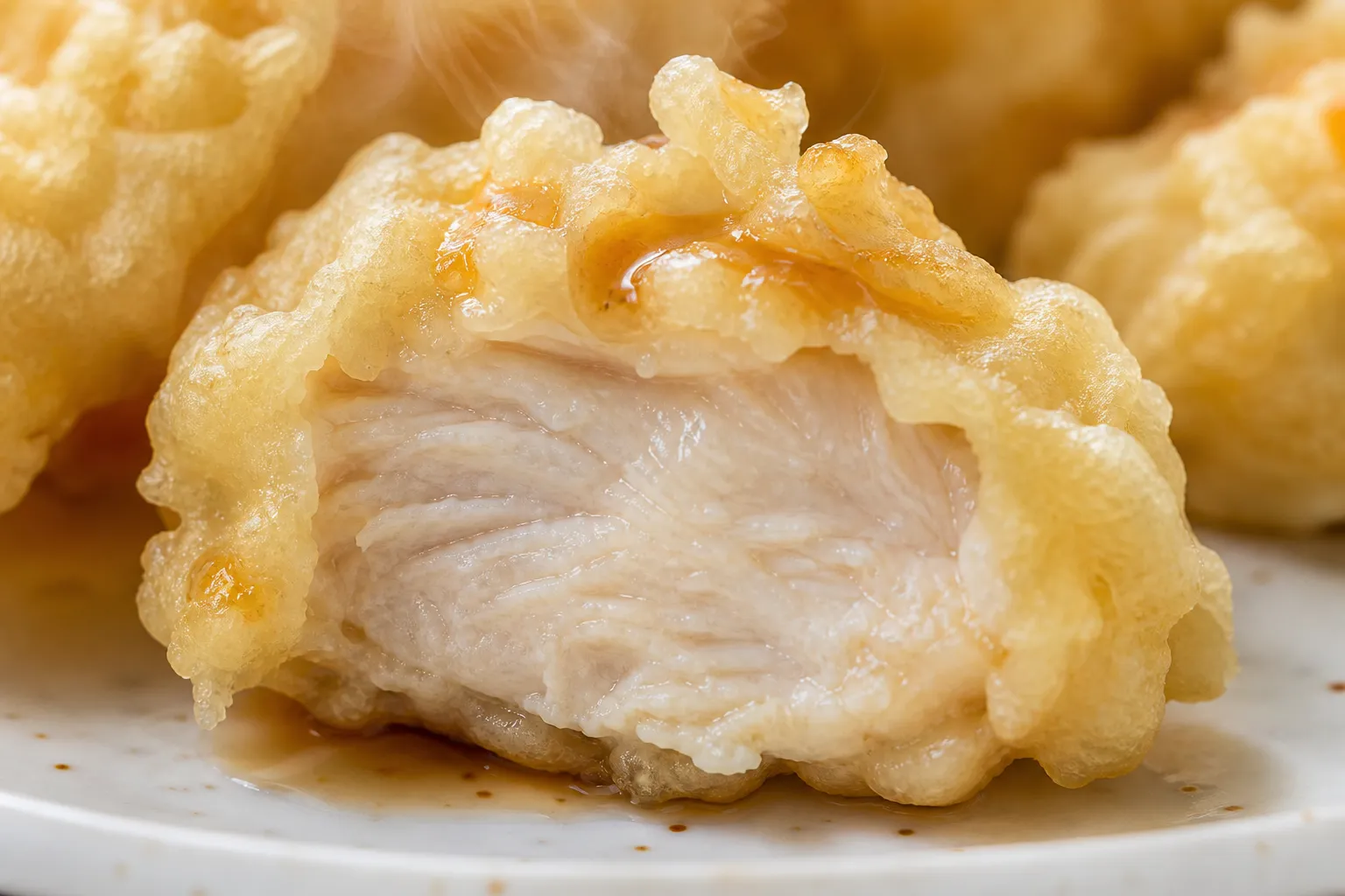 Close-up of toriten cut open showing juicy chicken inside a light tempura coating