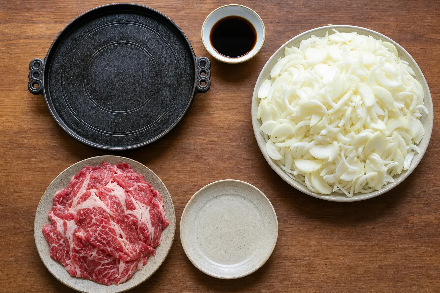Ingredients for Towada barayaki laid out: thin-sliced beef short rib, a large pile of sliced onion, and sweet soy sauce
