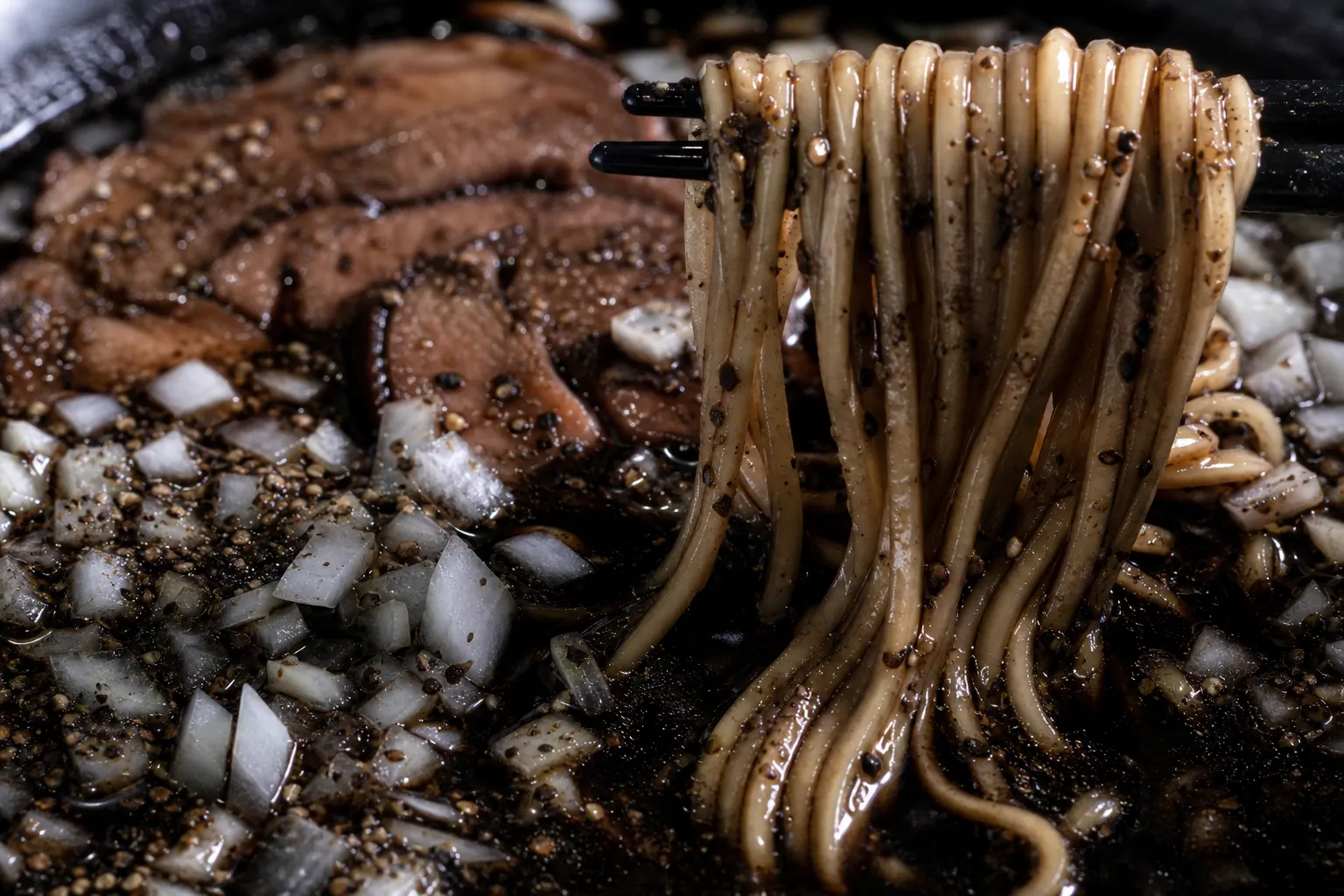 Close-up of the jet-black broth, black pepper, and raw onion of Toyama Black ramen